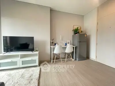 Modern living room with TV, dining area, and fridge in a stylish apartment.