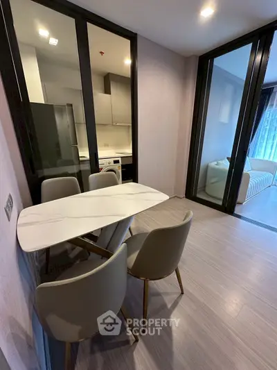 Modern dining area with sleek table and chairs, adjacent to a compact kitchen and cozy living space.