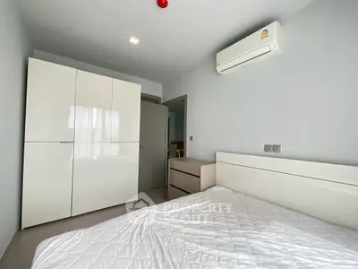 Modern bedroom with sleek white furniture and air conditioning unit