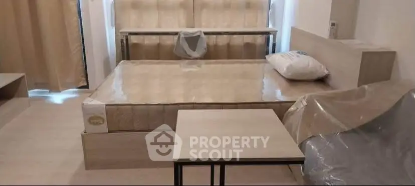 Modern bedroom with minimalist design and neutral tones, featuring a bed and small table.