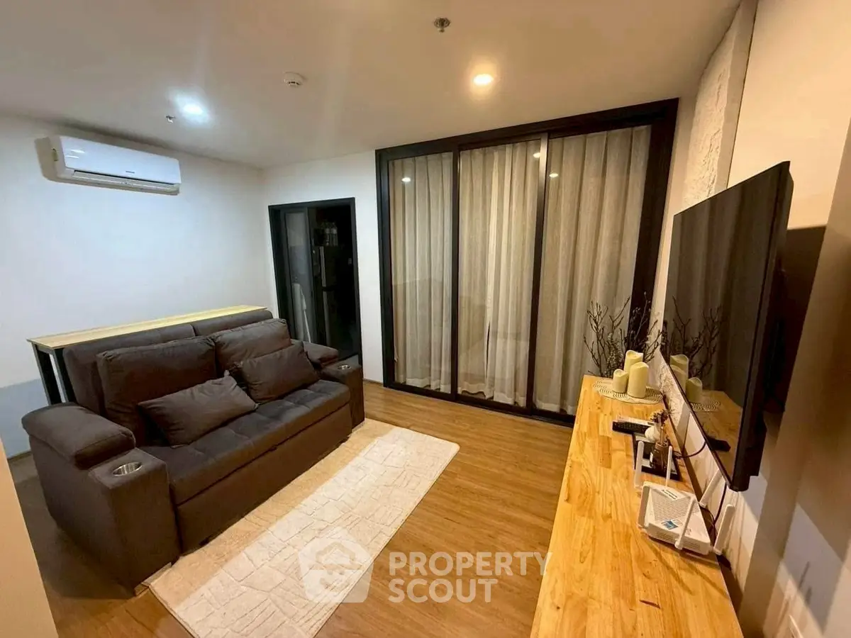Modern living room with cozy sofa and large TV, featuring wooden flooring and ambient lighting.