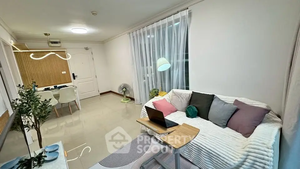 Modern living room with cozy sofa, stylish decor, and dining area in open layout apartment.