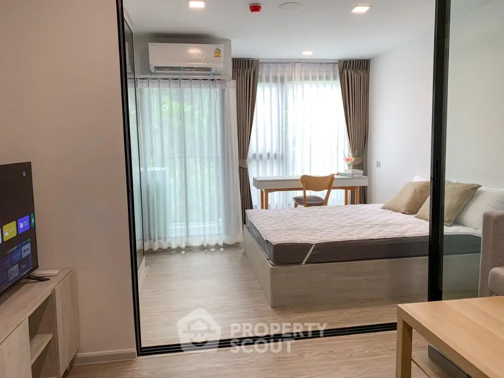 Modern bedroom with large windows and natural light, featuring a cozy bed and stylish decor.