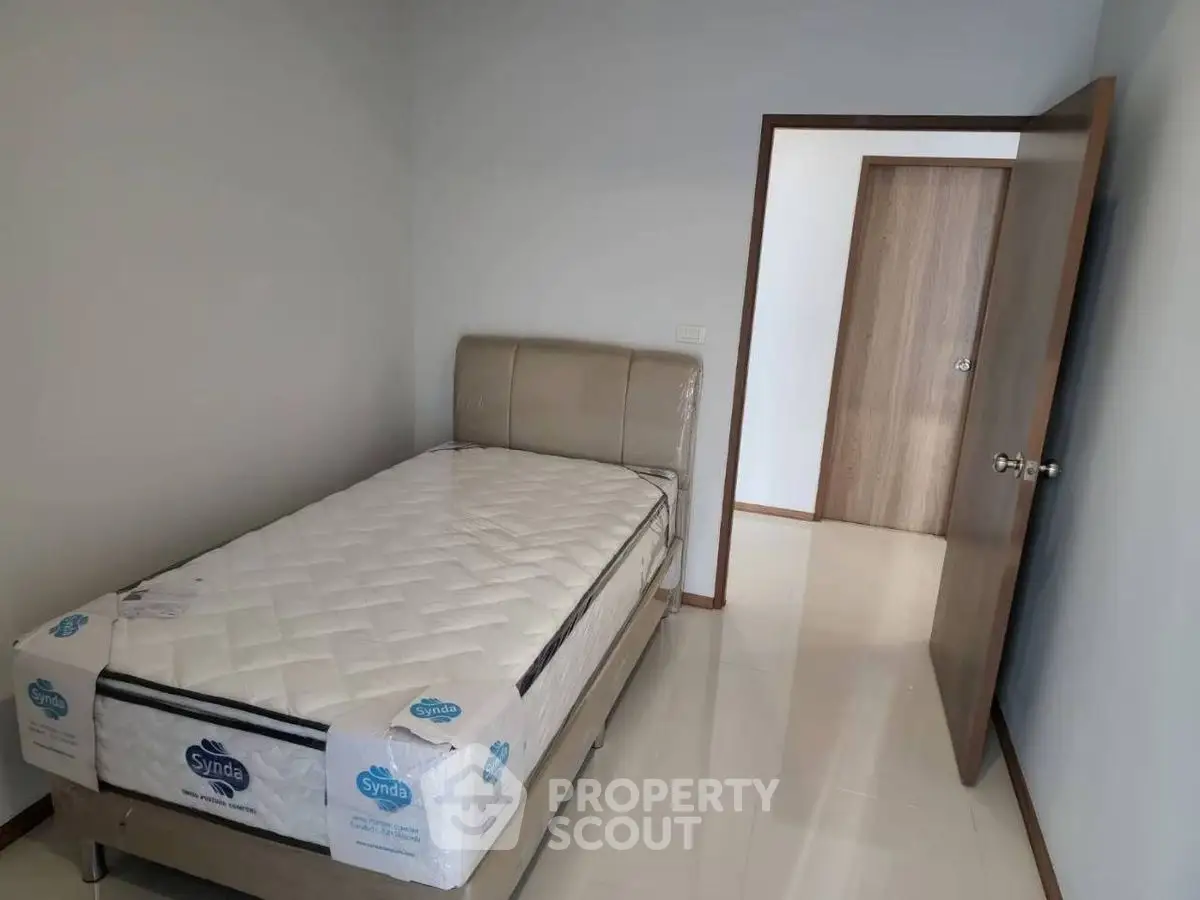 Modern minimalist bedroom with single bed and sleek wooden door