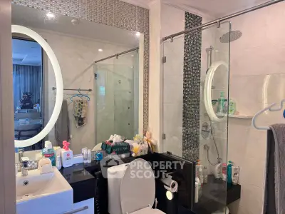 Modern bathroom with glass shower and illuminated mirror in stylish apartment.