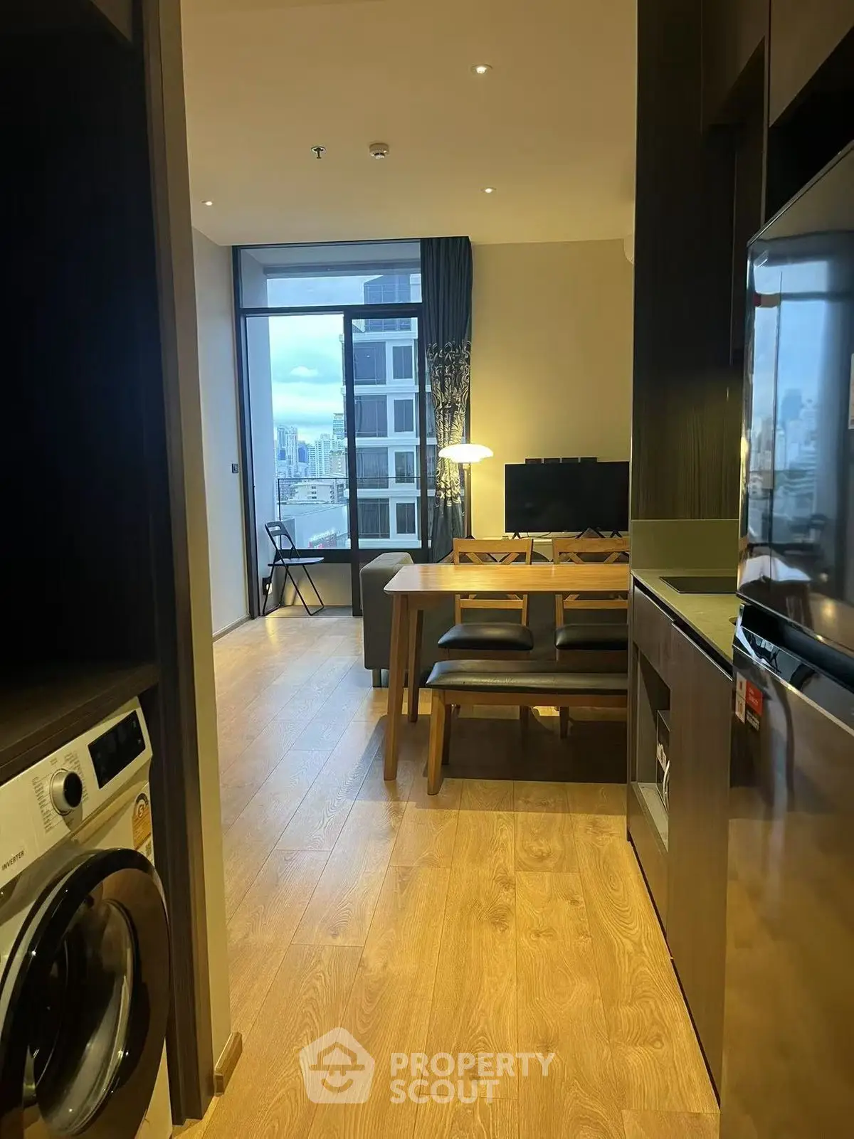Modern apartment interior with open layout, featuring a cozy living area and kitchen with wooden flooring.