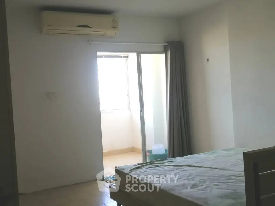 Cozy bedroom with air conditioning and balcony access for natural light.