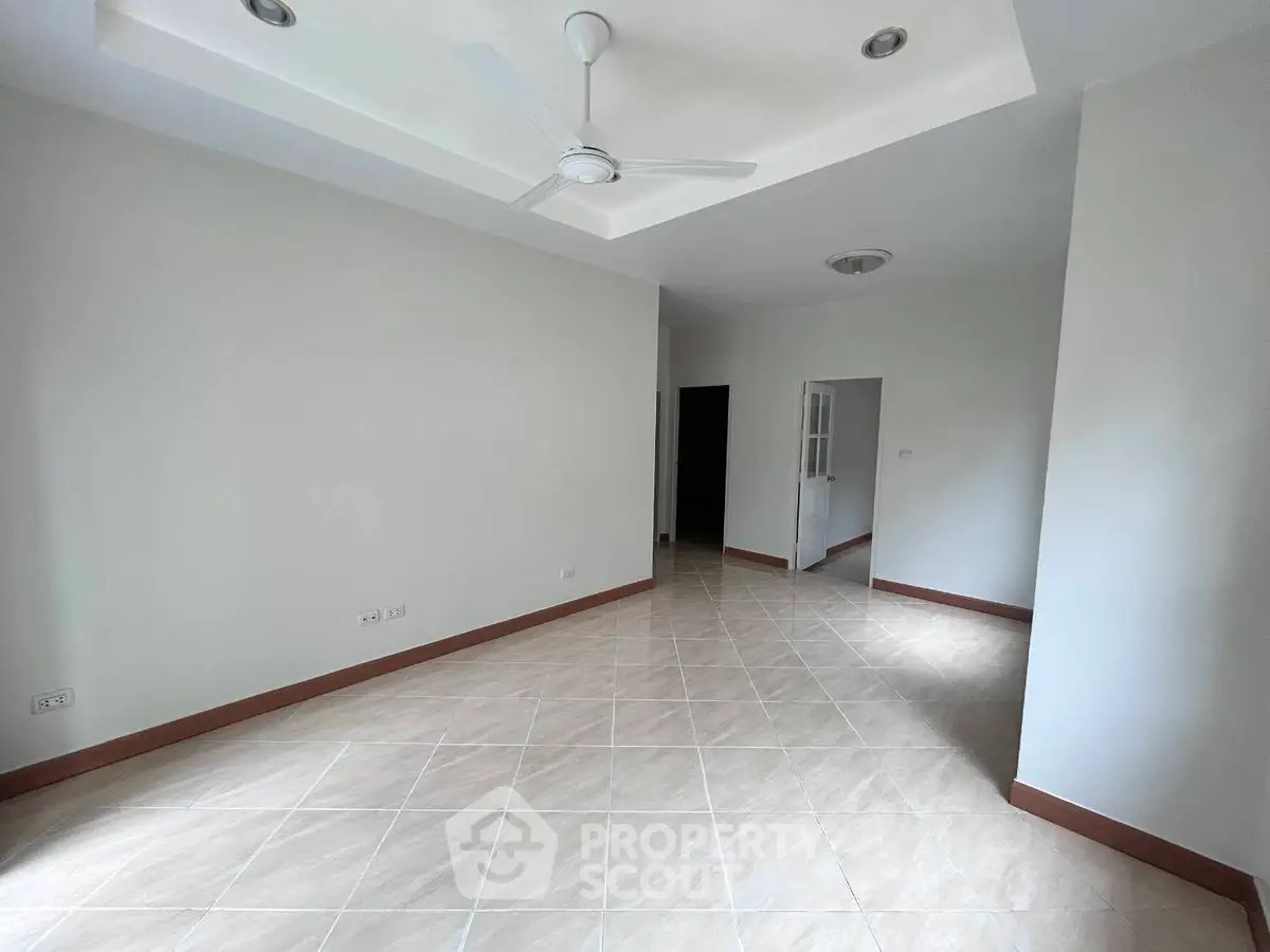 Spacious empty room with tiled flooring and ceiling fan, ready for customization.