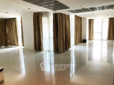 Spacious and sunlit living room with elegant curtains and glossy tiled flooring, perfect for modern living.