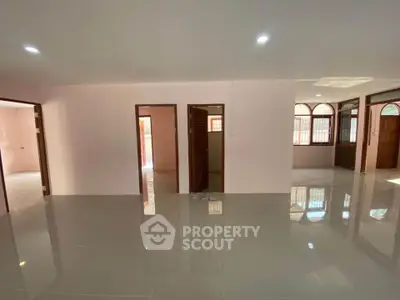 Spacious open-plan living area with glossy tiled floors and ample natural light.