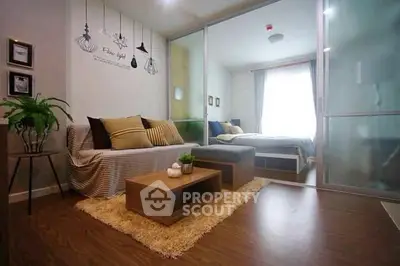 Modern studio apartment with cozy living area and stylish bedroom separated by glass doors.