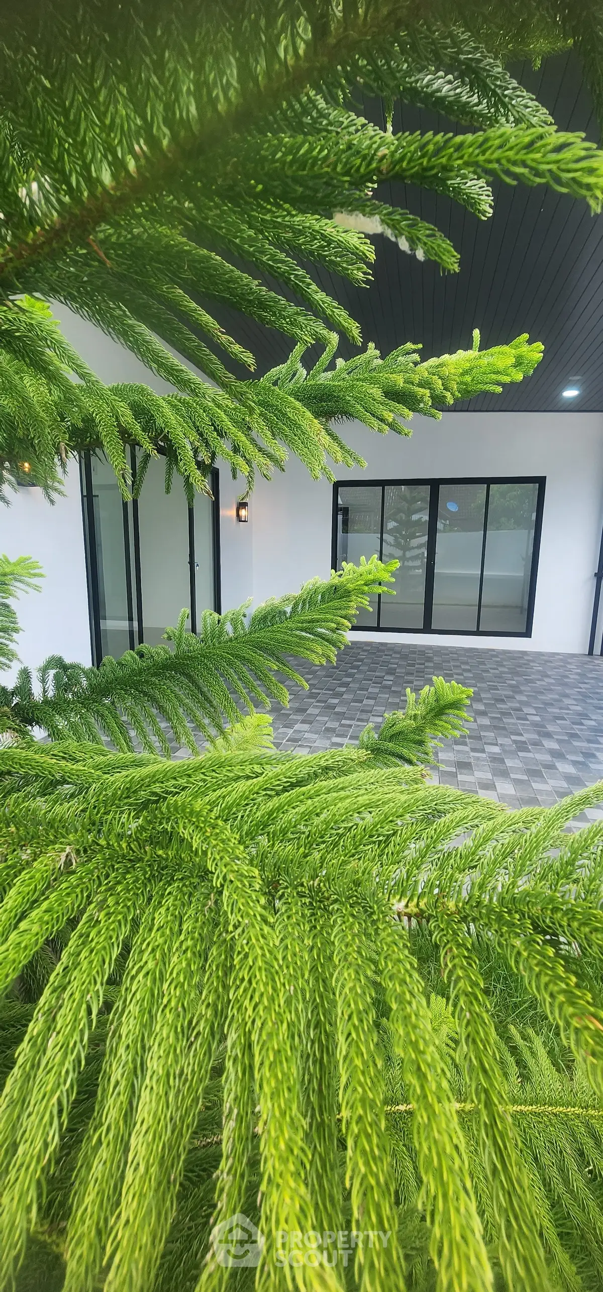 Modern building entrance with lush greenery and sleek glass doors.