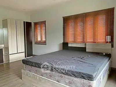 Spacious bedroom with modern decor and large windows for natural light.