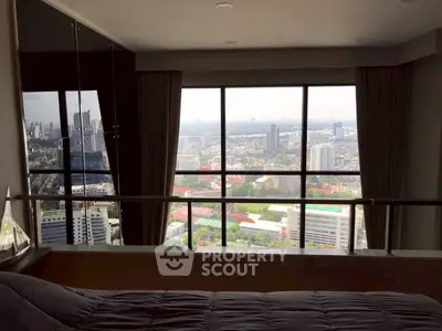 Luxurious bedroom with stunning city view from high-rise apartment window.