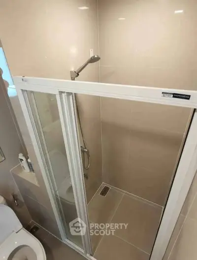 Modern bathroom with sleek shower enclosure and neutral tiles.