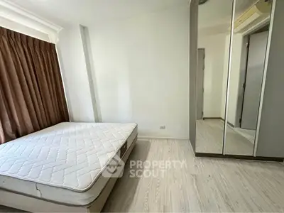 Spacious bedroom with large window and mirrored wardrobe in modern apartment.