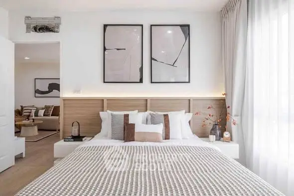 Modern bedroom with stylish decor and natural light, featuring cozy bedding and contemporary artwork.