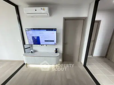 Modern living room with sleek TV setup and air conditioning, featuring minimalist design and light wood flooring.