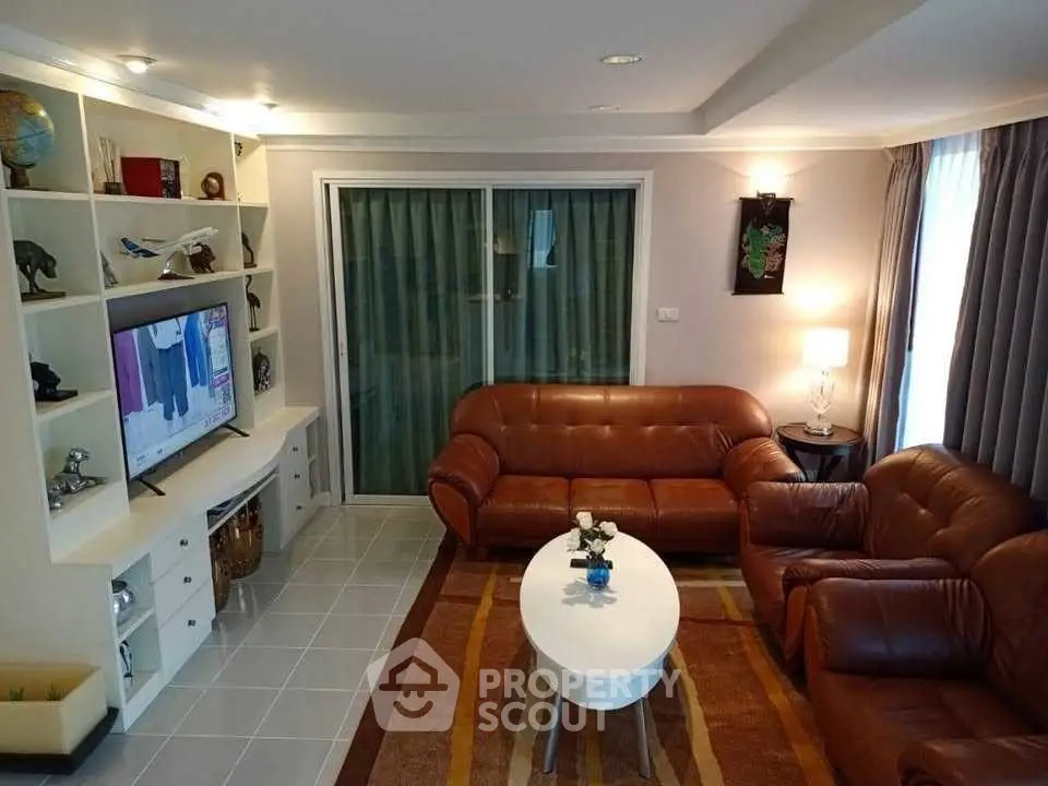 Cozy living room with leather sofas, modern TV unit, and elegant decor.