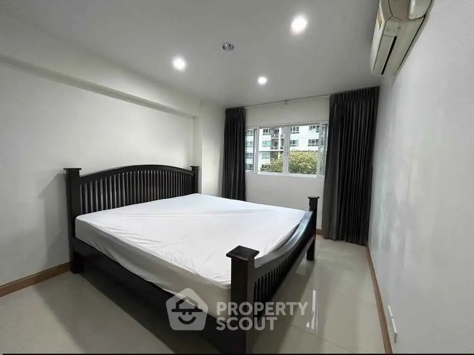 Spacious bedroom with modern bed and large window offering natural light.