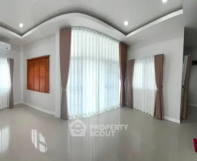 Spacious living room with large windows and elegant curtains in modern home.