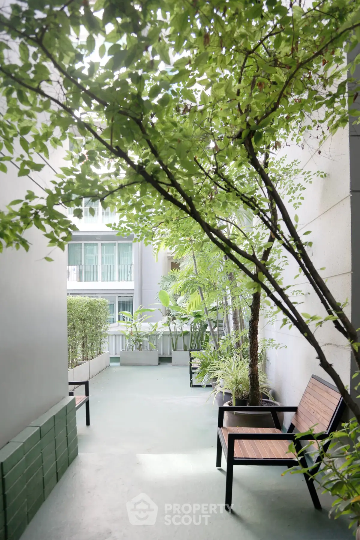Serene outdoor garden area with lush greenery and seating, perfect for relaxation in a modern residential complex.