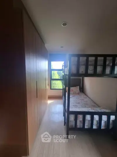 Cozy bedroom with bunk beds and large window offering natural light and scenic view.