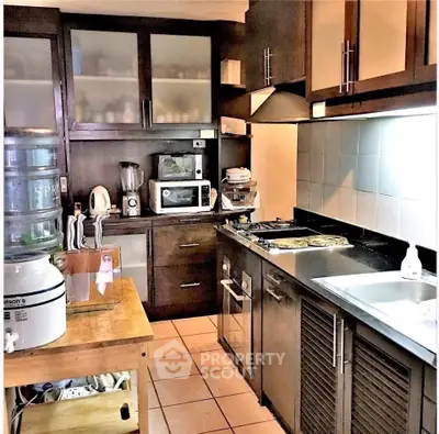 Modern kitchen with dark wood cabinets, gas stove, and sleek appliances for a stylish culinary experience.
