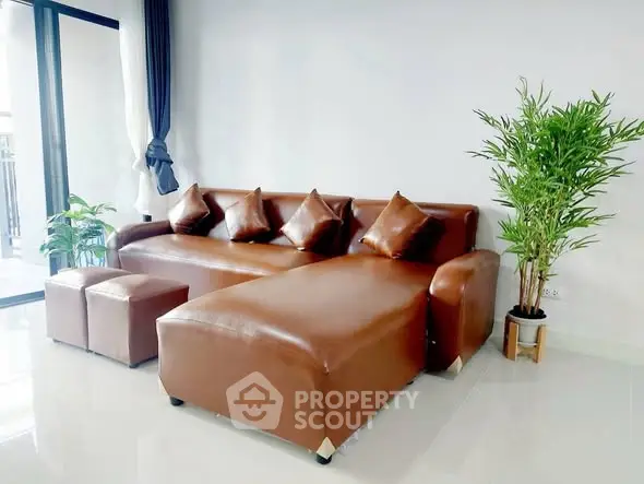 Modern living room with sleek brown leather sofa and lush green plant, perfect for stylish relaxation.
