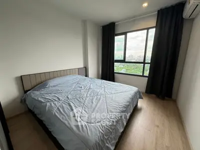 Modern bedroom with large window and city view, featuring cozy bed and minimalist decor.