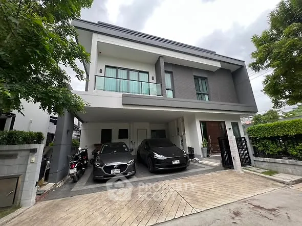 Modern two-story house with sleek design and spacious driveway in a serene neighborhood.