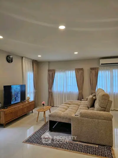 Spacious living room with modern sofa and entertainment center, perfect for relaxation and entertainment.