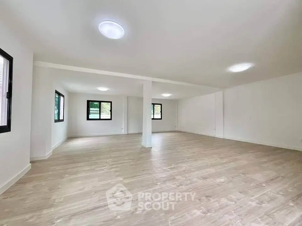 Spacious open-plan living area with large windows and wooden flooring
