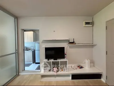Modern living room with open kitchen, featuring sleek TV stand and minimalist decor.