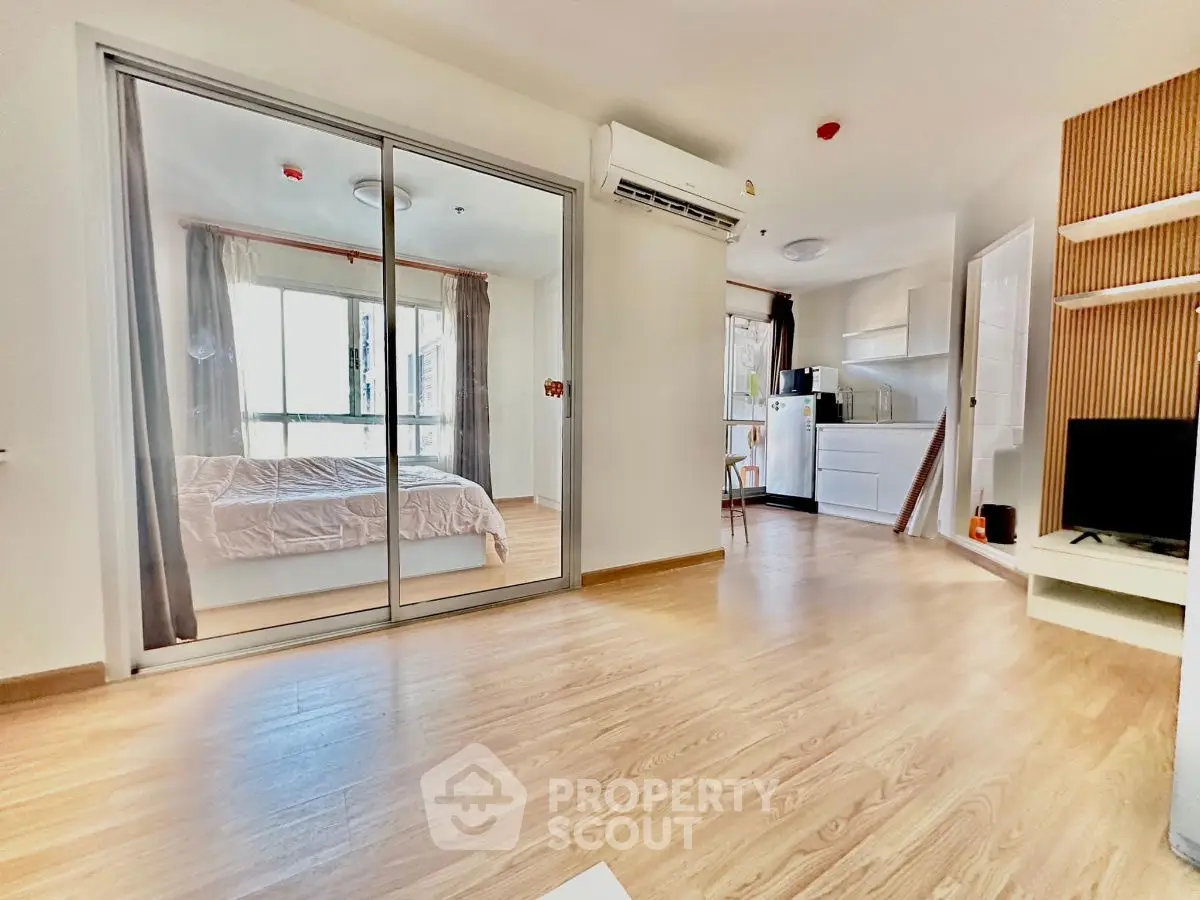 Modern apartment interior with open layout, featuring bedroom and kitchen areas.