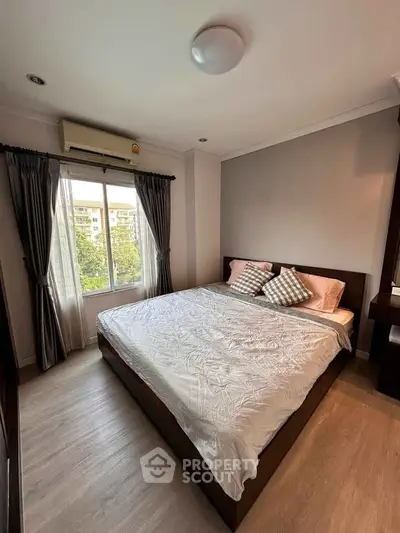 Cozy bedroom with large window and modern furnishings in a stylish apartment.