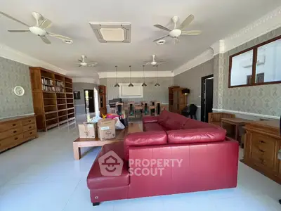 Spacious living room with red leather sofa and elegant wooden furniture, perfect for family gatherings.