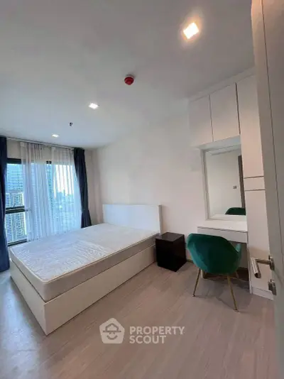 Modern bedroom with city view, featuring sleek furniture and ample natural light.