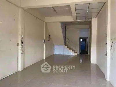 Spacious empty interior with tiled floor and staircase, ideal for customization.
