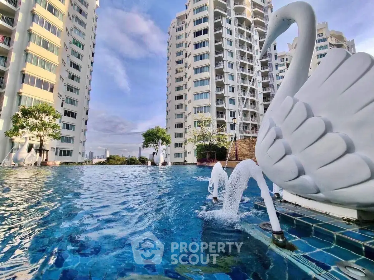 Luxurious high-rise apartment complex with stunning pool and elegant swan sculptures.