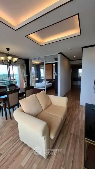 Spacious living room with elegant dining area and cozy seating, featuring modern lighting and wooden flooring.