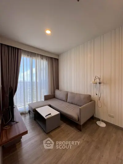 Modern living room with cozy sofa and floor lamp, featuring large window with city view.