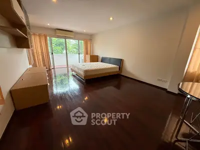 Spacious bedroom with polished wooden floors and balcony access, perfect for modern living.