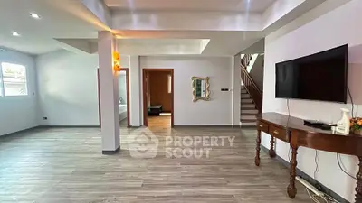 Spacious modern living room with sleek flooring and wall-mounted TV, perfect for entertaining.