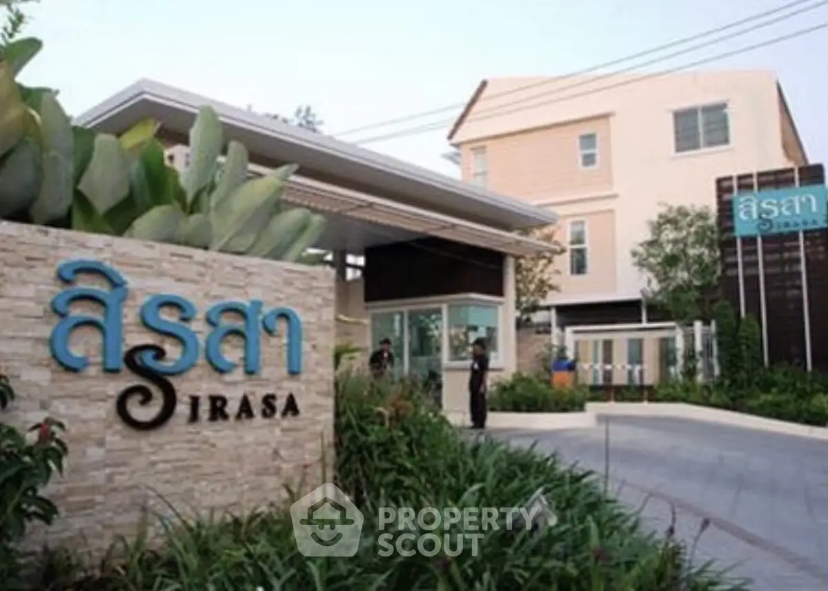 Modern residential building entrance with lush landscaping and stylish signage.
