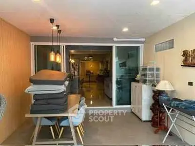 Spacious dining area with modern lighting and sliding glass doors leading to a cozy living room.