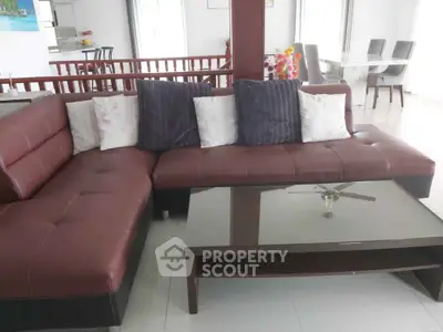 Spacious living room with modern brown leather sectional sofa and glass coffee table, perfect for relaxation.