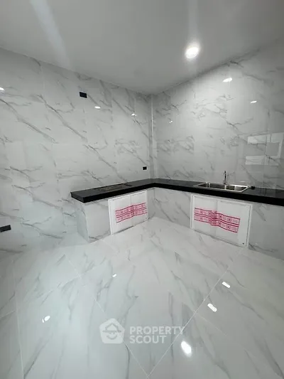Sleek modern kitchen with marble tiles and black countertops, perfect for culinary enthusiasts.