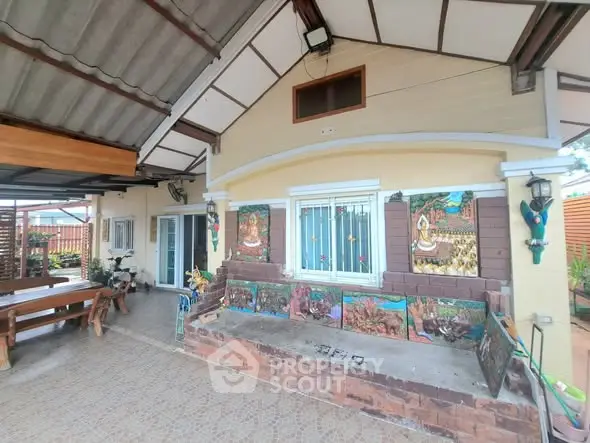 Charming outdoor patio with artistic wall decor and cozy seating area, perfect for relaxation and gatherings.