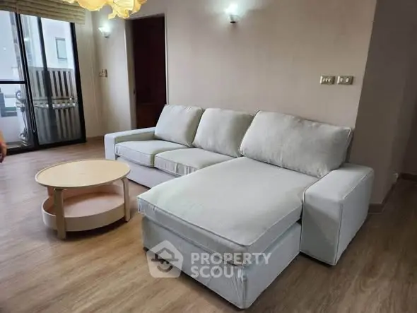 Spacious living room with modern sectional sofa and wooden flooring, perfect for relaxation.